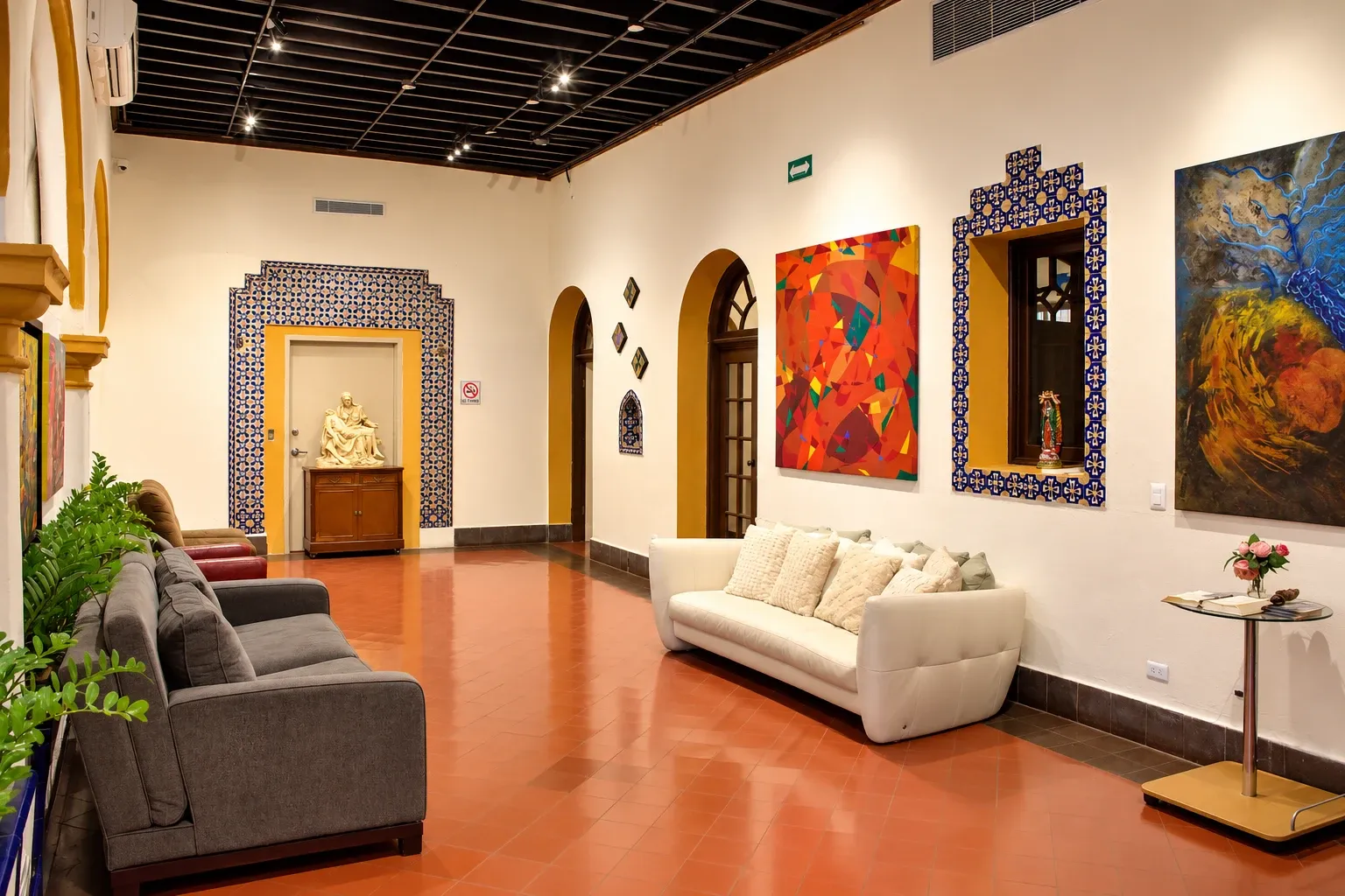 Pasillo principal con sillón blanco, azulejos y pinturas